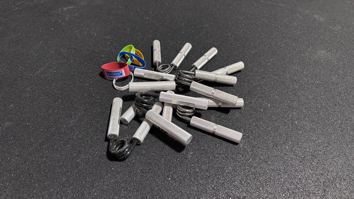 Three types of grip strength trainers: Captains of Crush grippers, a Heavy Grips grippers, and Ironmind extensor bands.