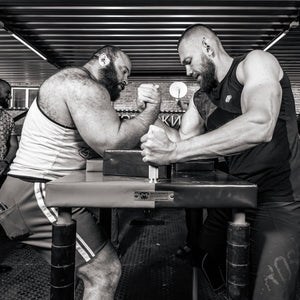 Two men gripping up at an arm wrestling table.