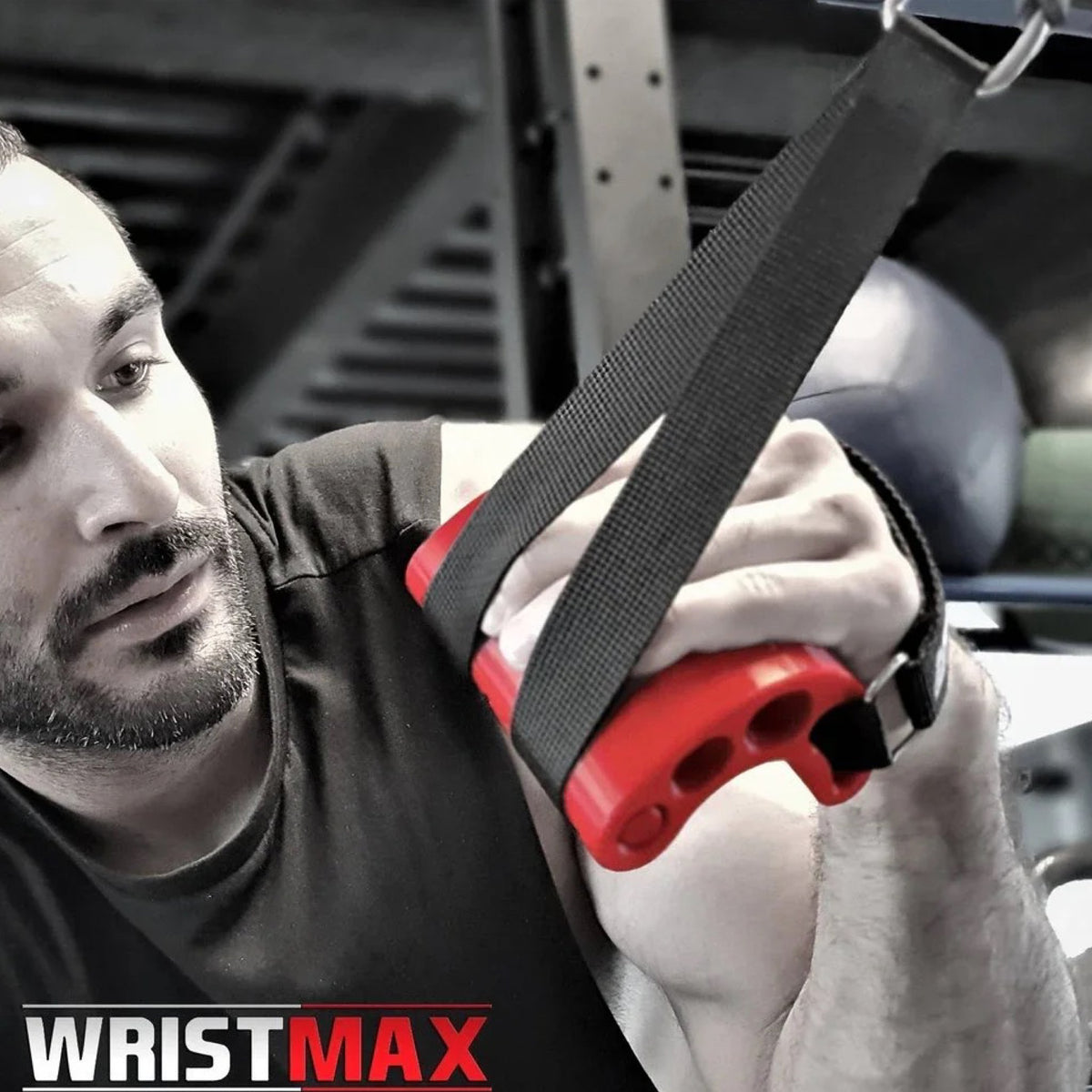 Arm wrestler training with the WristMax wrist trainer hanging from a cable strap in a gym