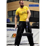 Very muscly man in a yellow, sponsorship t-shirt lifting two large weights with a pinch grip via an IronMind® Hub.