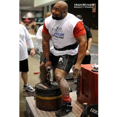 A weightlifter strains to lift a stack of heavy weights in a deadlift using the Rolling Thunder® handle.