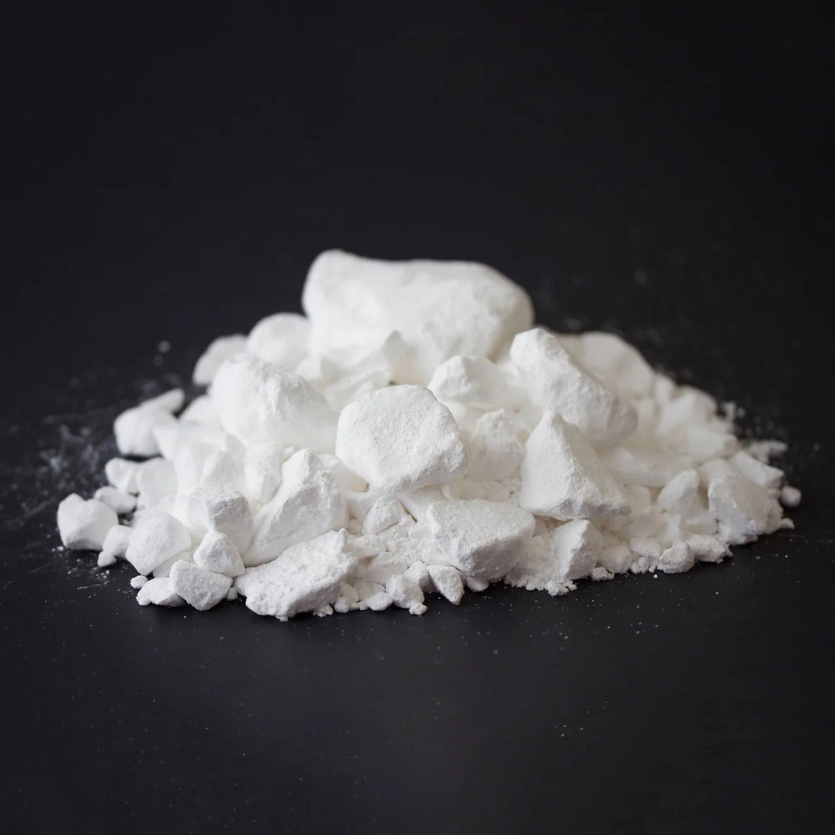 Pile of Metolius Super Chalk, chunks and fine powder, on a black surface