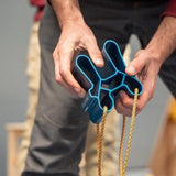 A rock climber holds the Quad Block in a pinch grip position.